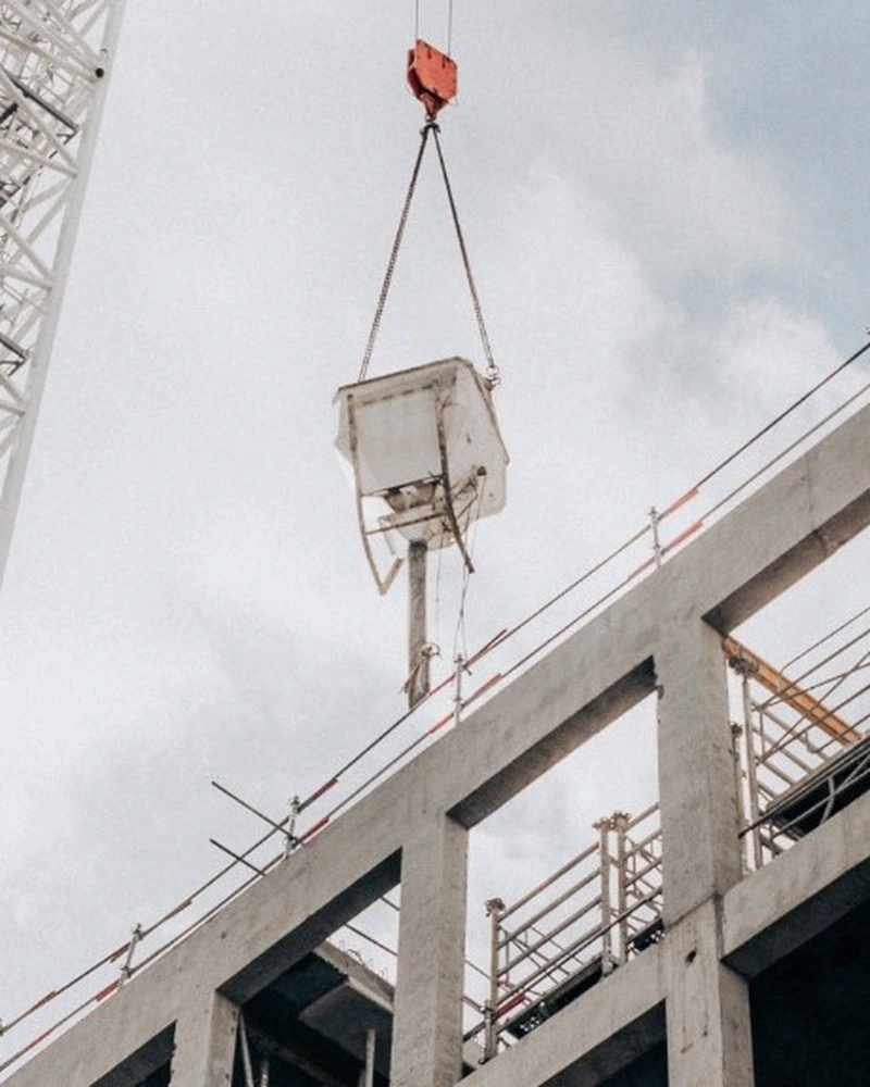 Crane lifting concrete at a high-rise construction site