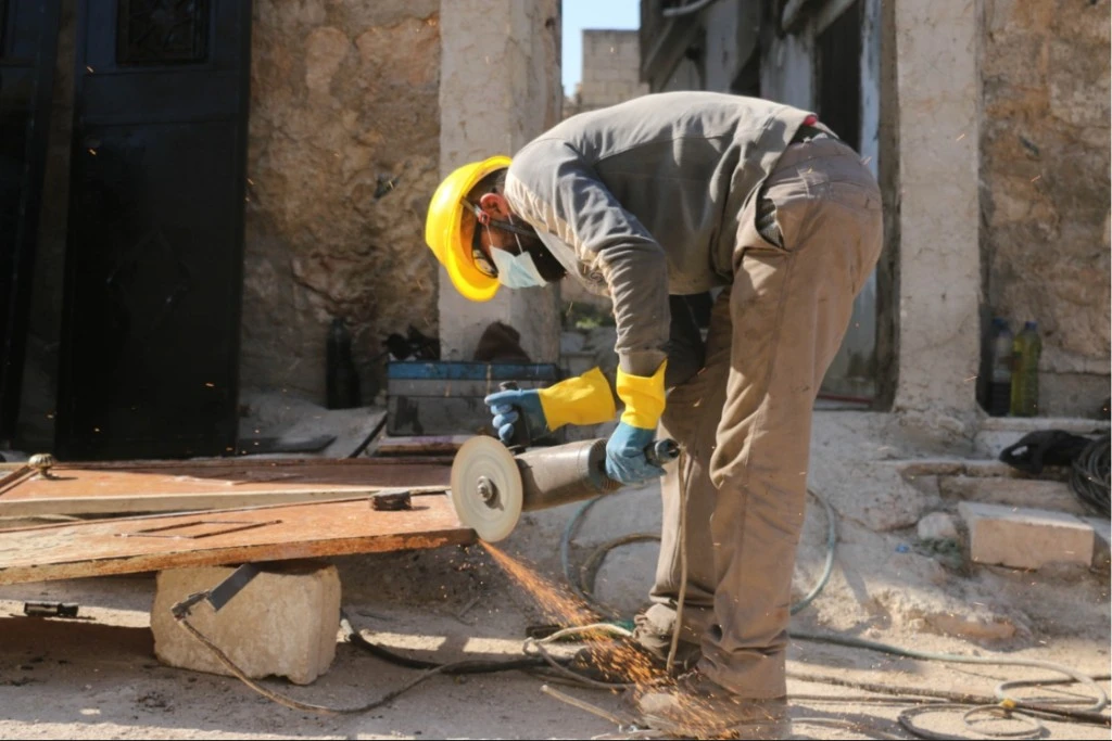 Construction worker using a grinder with safety equipment